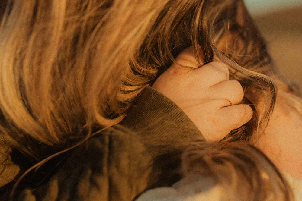 Young son grabs mom's hair for comfort in golden light